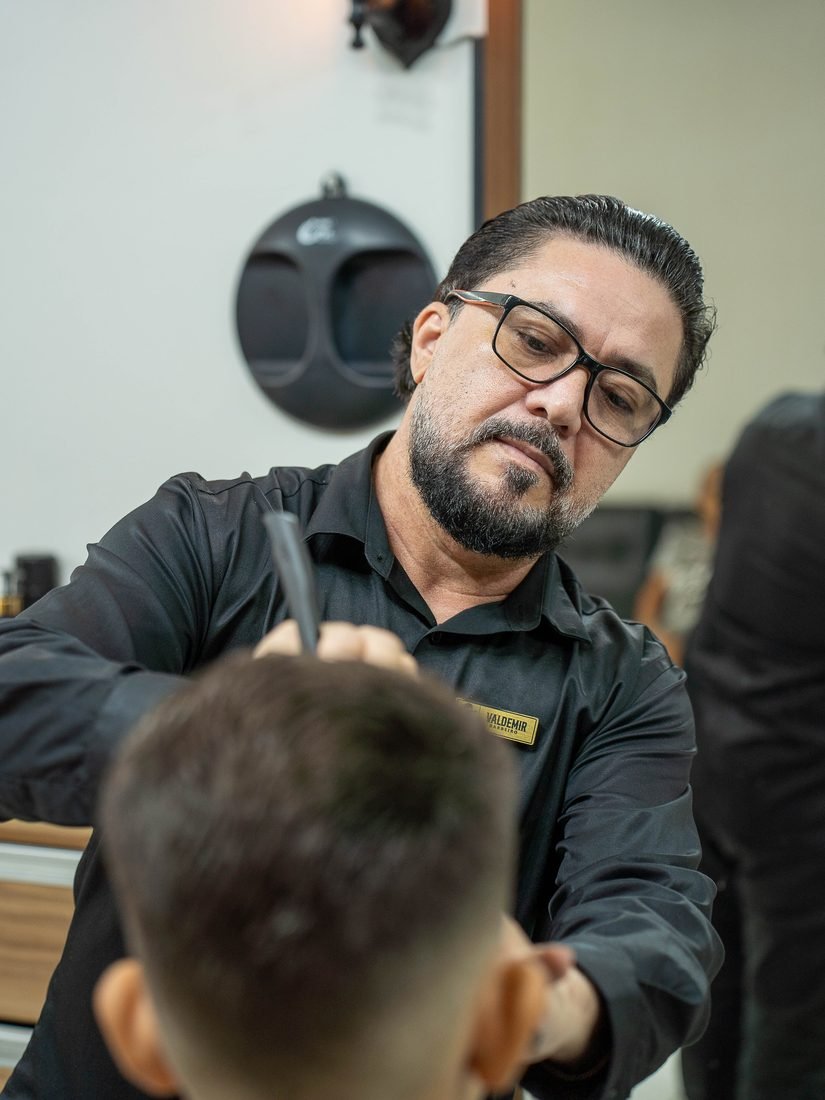 Veras concentrado cortando o cabelo de um cliente