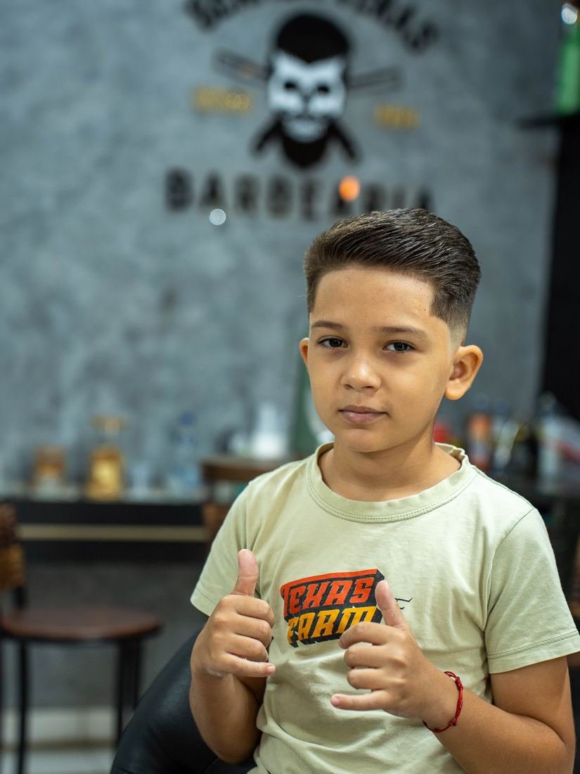 Menino sorrindo com o polegar para cima após o corte