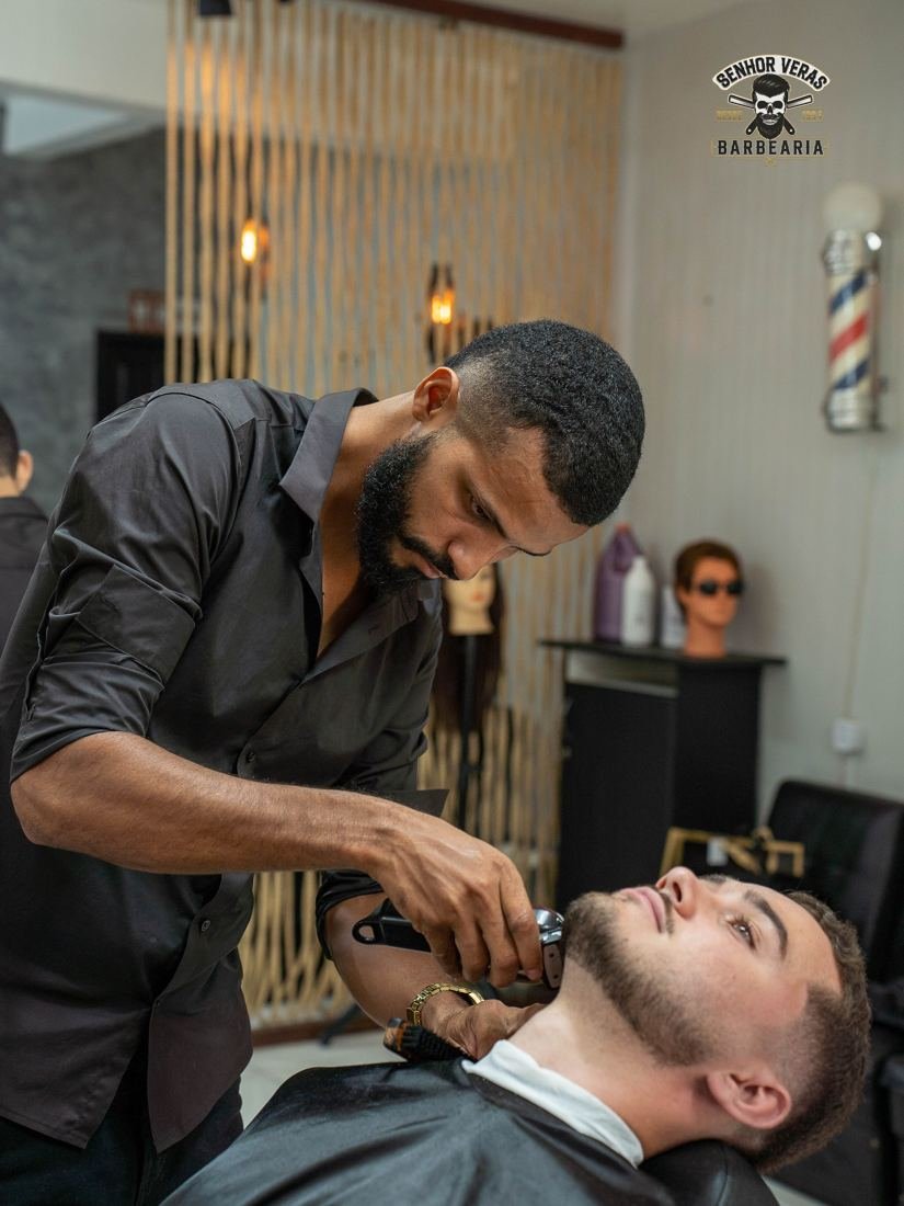 Barbeiro cuidando da barba de um cliente na cadeira reclinada