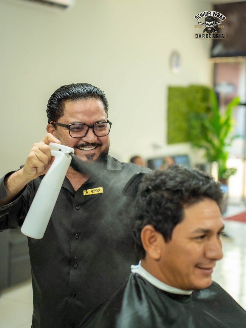 Veras borrifando água no cabelo de um cliente sorridente